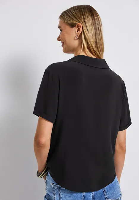 Frau mit schwarzen Kurzarmhemd und Jeans von hinten.